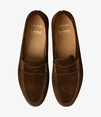 A bird's-eye view presenting a pair of Loake Jefferson Brown Suede Loafers, perfectly aligned to showcase their symmetrical design and meticulous craftsmanship. The rich brown suede and fine stitching details are evident from this perspective, epitomizing timeless style and refinement.