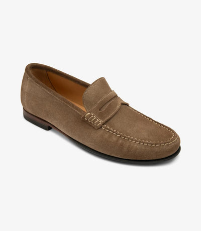 An angled shot highlighting the elegant contours and craftsmanship of the Loake Jefferson Flint Suede Loafer. The supple suede leather gleams under the light, while the moccasin leather/rubber soles provide durability and grip.