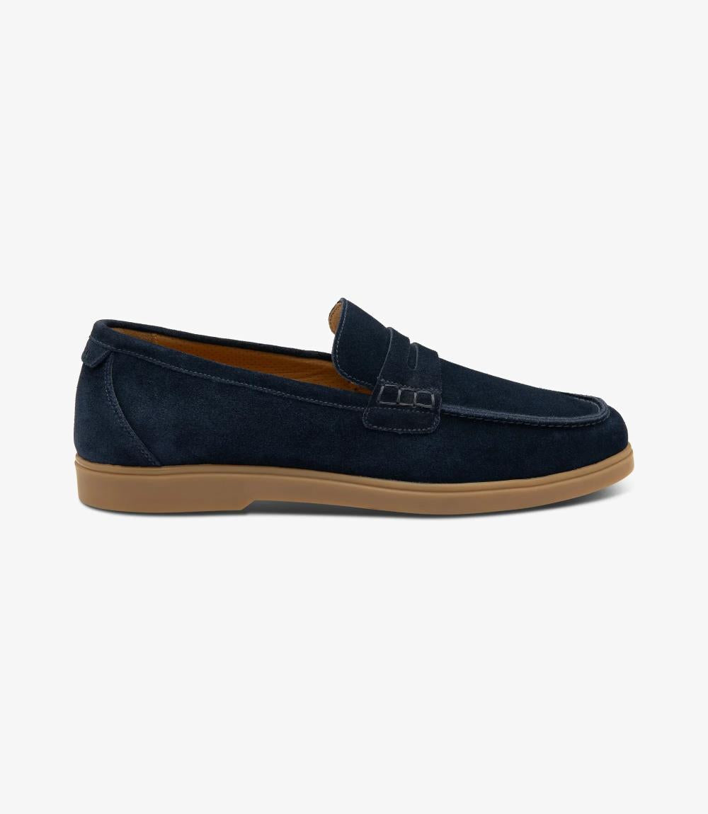 A side view capturing the sleek silhouette of the Loake Lucca Navy Suede Loafer, showcasing its refined design and premium suede material. The saddle apron detail adds a touch of sophistication to the ensemble.