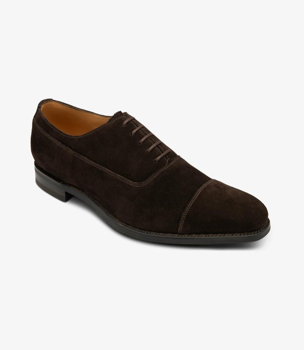 From a dynamic angle, the Loake Truman Dark Brown Suede Oxford reveals its meticulous craftsmanship and attention to detail. The rich dark brown suede leather shines under the light, exuding sophistication and elegance. The sleek profile of the shoe highlights its timeless appeal and versatility.