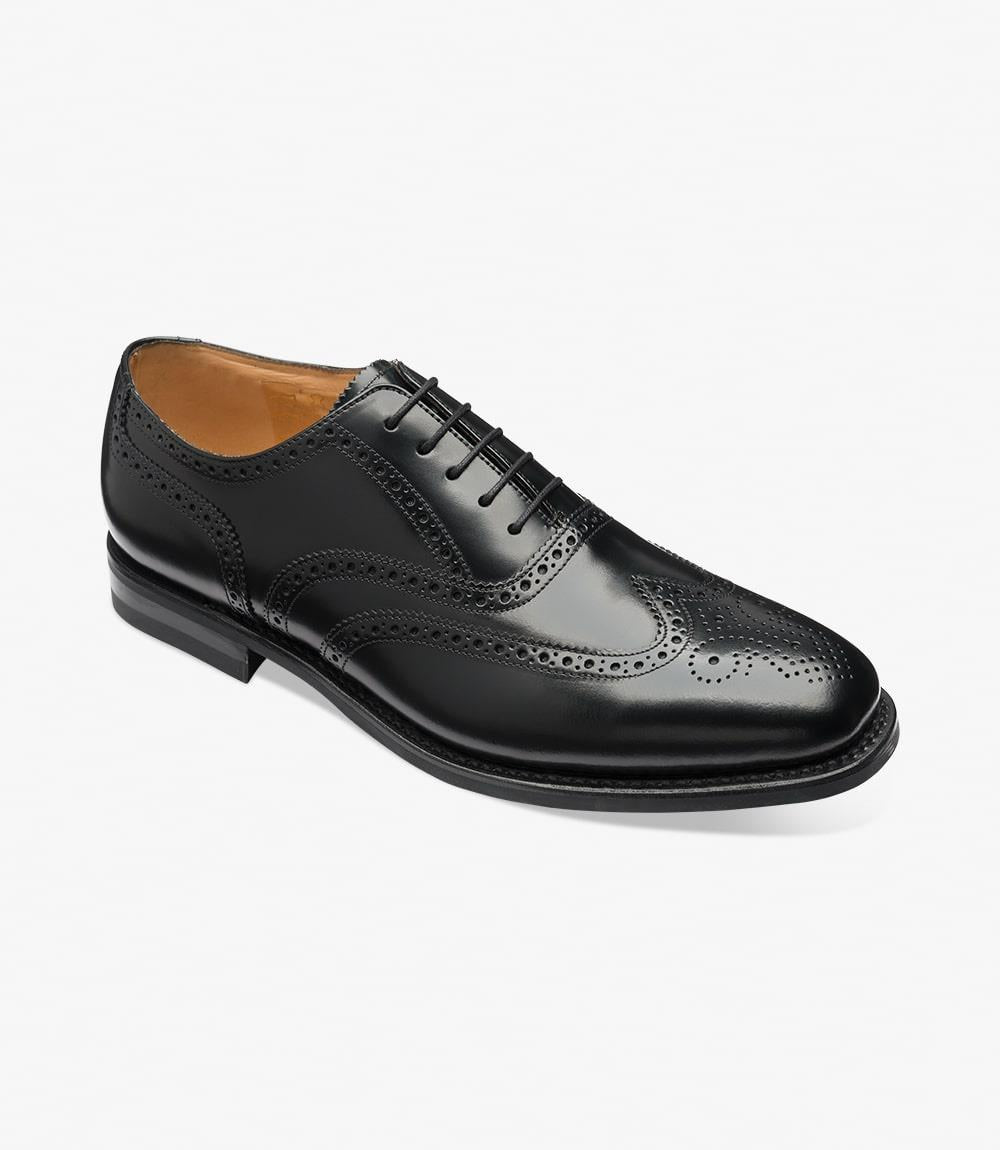 An angled shot capturing the dynamic lines and contours of the Loake 302 Black Leather Oxford Brogues. The rich black leather and classic brogue detailing are highlighted from this perspective, emphasizing the timeless elegance of these shoes.