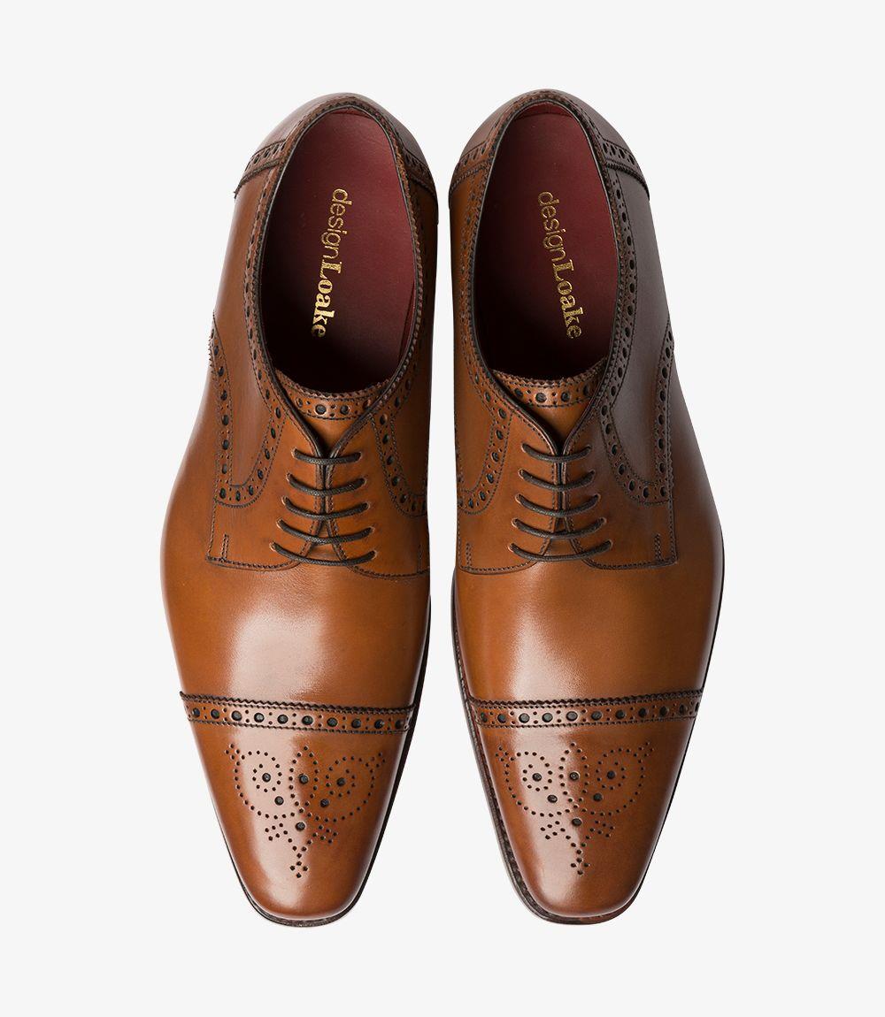 This overhead shot showcases both Loake Foley Cedar Semi Brogues side by side. The symmetry of the shoes highlights their meticulous craftsmanship and attention to detail. The rich cedar leather gleams under the light, while the intricate punched decoration around the toe caps creates visual interest. The Goodyear welted soles are prominently displayed, underscoring the durability and support these shoes offer.
