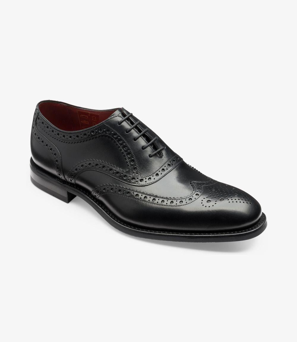 From an angled perspective, the Kerridge Black Oxford exudes sophistication with its polished black leather finish and finely crafted brogue detailing. The intricate spider brogue pattern on the toe and quarters adds a touch of elegance, while the Claridge last shape lends a subtly elongated appearance. The robust rubber sole is partially visible, emphasizing both its durability and style, making it suitable for various occasions.
