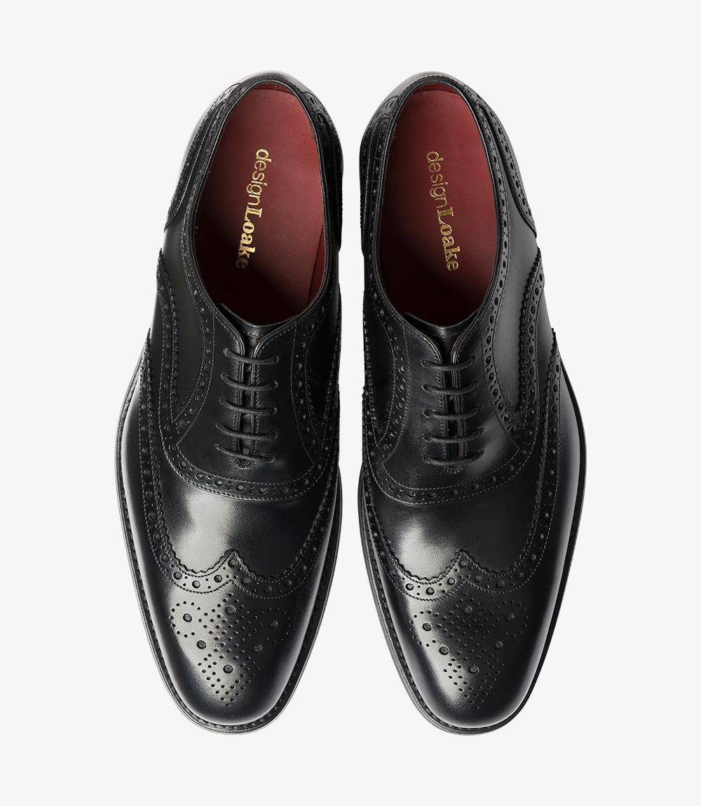 In the top view, the pair of Kerridge Black Oxfords reveals a harmonious design with symmetrical brogue detailing across the toe caps and classic Oxford lacing that highlights their traditional style. The rich black leather has a smooth, lustrous finish, while the subtle elongation in the toe enhances its sophisticated silhouette. The leather-lined interiors offer a glimpse of the quality craftsmanship that ensures comfort, making these shoes an exceptional addition to any wardrobe.