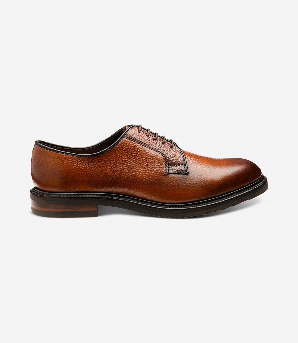 A side view of the Loake Leyburn Mahogany Derby Toe Cap shoes, showcasing their sleek silhouette and premium hand-painted mahogany grain calf leather upper. The Goodyear welted shadow rubber soles are prominently featured, symbolizing durability and quality craftsmanship.
