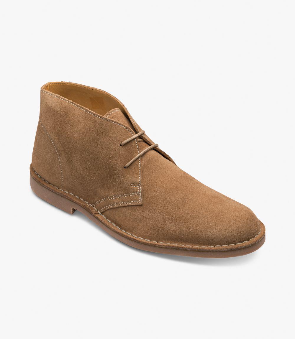 The angled view of the Loake Sahara Chukka Boot captures its stylish design and craftsmanship. This perspective highlights the gentle curvature of the boot’s upper, which seamlessly transitions into the comfortable collar. The three-eyelet lacing system is prominently displayed, offering an adjustable fit that complements the boot's sophisticated profile. The rubber sole is partially visible, emphasizing its practical construction and grip capabilities, while the rich tan color of the suede radiates warmth