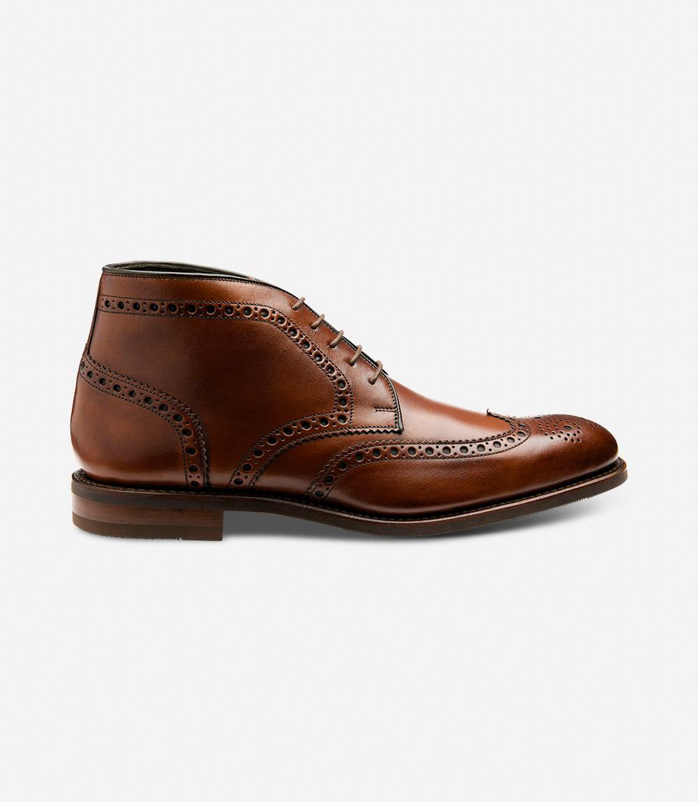 The Loake Sywell Cedar Brogue Boots exhibit a sleek silhouette, showcasing the intricate brogue detailing and hand-painted calf leather, accented by the durable commando rubber sole, combining style and functionality.