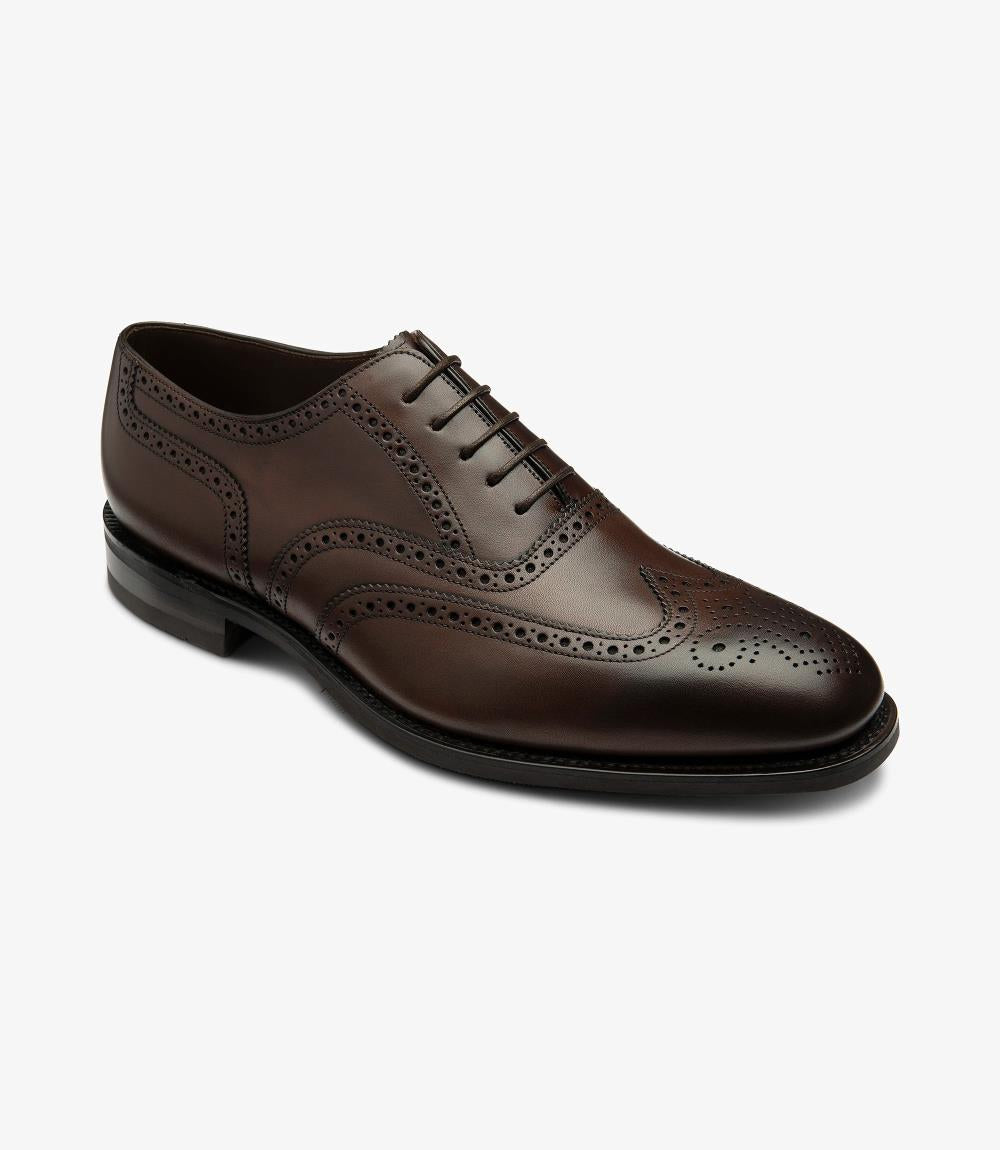 This angle highlights the classic silhouette of the brogue, emphasizing the chiseled toe and the meticulously crafted brogue patterns. The side profile reveals the smooth curvature of the leather, complemented by the subtle sheen that enhances its luxurious appearance. The rubber sole's flexibility is visible, indicating comfort and durability for everyday wear.