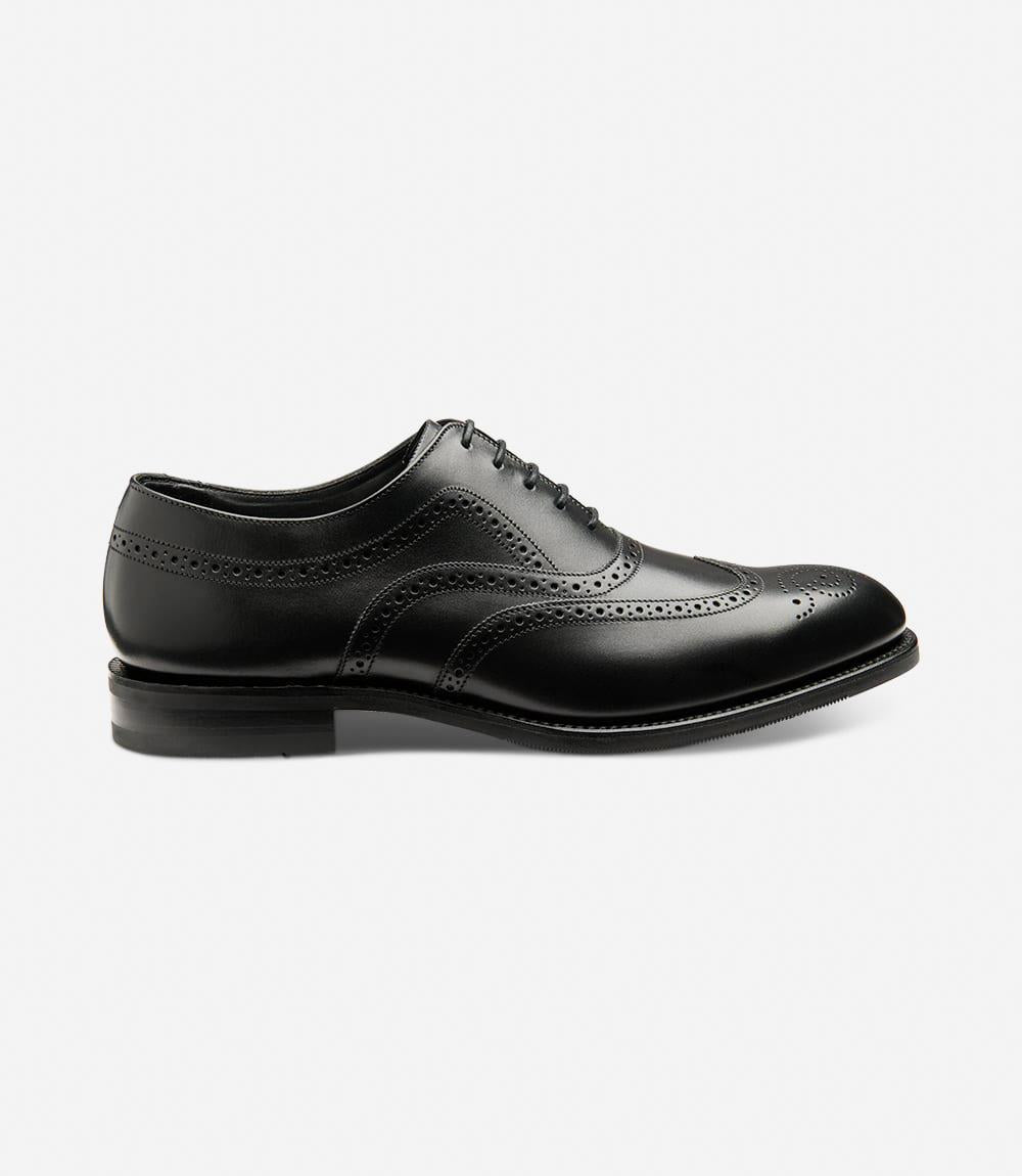 Showcases the sleek silhouette of the black calf leather brogue with intricate wingtip detailing and classic perforations. The Goodyear welted shadow rubber sole is prominently visible, highlighting its durability and craftsmanship.