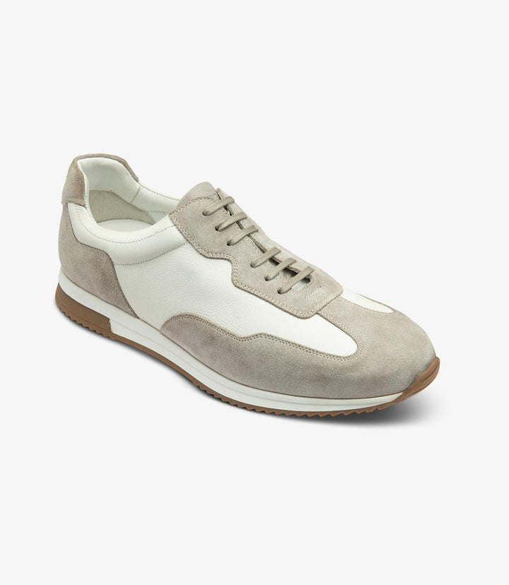 An angled shot of the Loake Linford White-Grey Leather Trainer, highlighting the elegant curves, the detailed stitching, and the contrast between the white and grey leather sections.