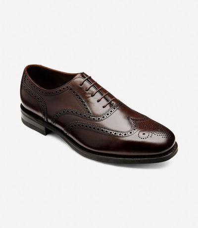An angled shot capturing the intricate brogue detailing and craftsmanship of the Loake 302 Brown Leather Oxford Brogues. The polished leather shines in the light, highlighting the quality and sophistication of these shoes from a unique perspective.