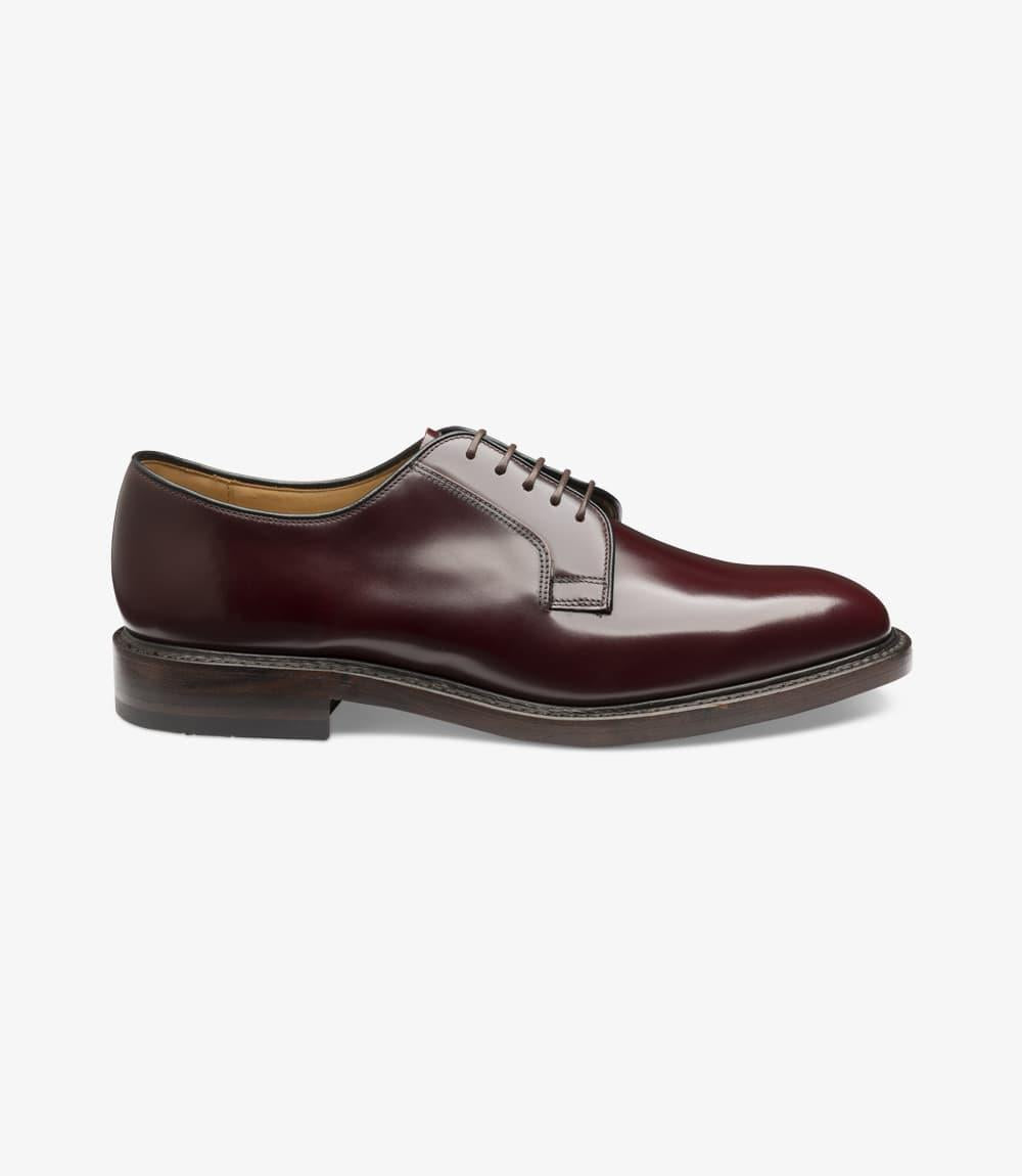A close-up of the Loake 771 Burgundy Derby shoe from the side, showing the polished burgundy leather with a smooth finish, plain toe design, and subtle stitching along the Goodyear Welted double leather sole. The classic silhouette and slightly angled heel are visible, showcasing the shoe’s elegant structure.