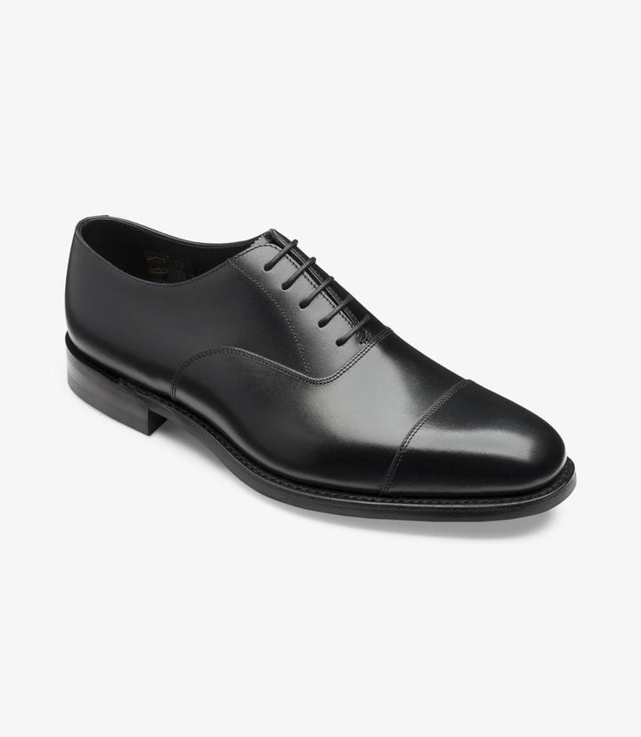 This angled shot captures the Loake Aldwych Oxford from a dynamic perspective. The curvature of the shoe is emphasized, showcasing the refined craftsmanship and attention to detail. The Toe Cap design is prominent, giving the shoe a distinguished look. The slight elevation of the heel adds a touch of formality, while the rubber sole is partially visible, hinting at both style and functionality.