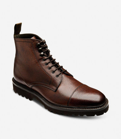 From a dynamic angle, the Aquarius boot showcases its impeccable craftsmanship and modern design. The dark brown grain leather gleams under the light, while the commando rubber sole adds traction and stability. The angled view emphasizes the boot's sophisticated profile and rugged charm.