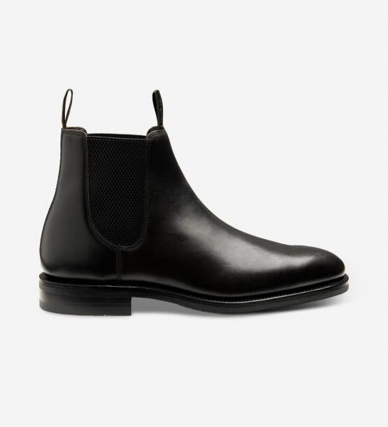 A striking image capturing the Loake Emsworth Black Chelsea Boots in all their refined glory. The sleek silhouette of the Chelsea design is complemented by the rich calf leather upper, while the Goodyear welted shadow rubber soles signify durability and quality. This image exudes sophistication and classic style, making these boots a quintessential addition to any gentleman's wardrobe.