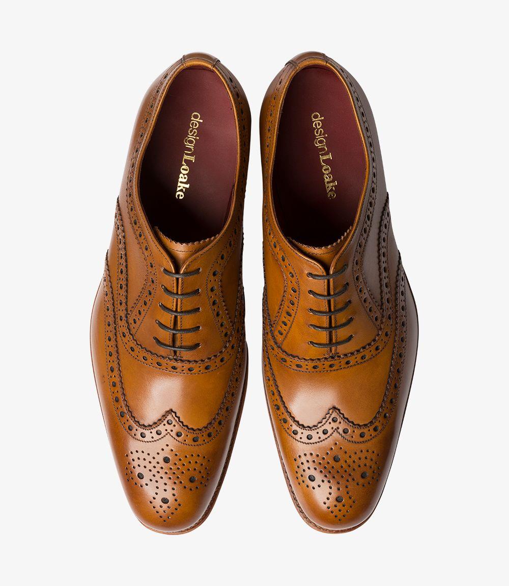 The top-down view of the Loake Fearnley Tan Oxford Brogues reveals their symmetry and stylish design. Both shoes are displayed side by side, showcasing the classic brogue perforations and the smooth leather finish. The layout highlights the well-defined toe shape and the elegance of the overall design. The Goodyear welted soles are also visible, emphasizing the quality construction that characterizes this exceptional pair of men’s shoes. 