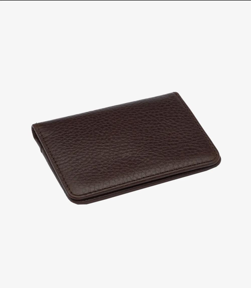 The closed view of the Loake Fenchurch Dark Brown Grain Wallet highlights its elegant and structured design. Crafted from premium dark brown grain leather, the wallet features a textured surface that adds a touch of sophistication. Its compact dimensions make it easy to carry, while the understated design ensures it complements any style. The wallet's edges are neatly stitched, showcasing the meticulous craftsmanship that Loake is known for. 