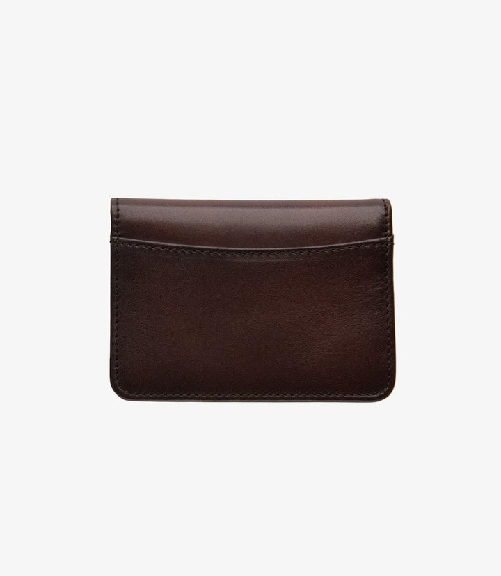 The closed view of the Loake Fenchurch Dark Brown Wallet showcases its sleek and refined silhouette. Made from premium dark brown calf leather, the wallet features a smooth, rich texture that highlights its luxurious finish. The embossed Loake logo on the front adds a subtle touch of sophistication, reflecting the brand's commitment to quality. Its compact size allows for easy storage in pockets or bags, making it a practical choice for everyday use.