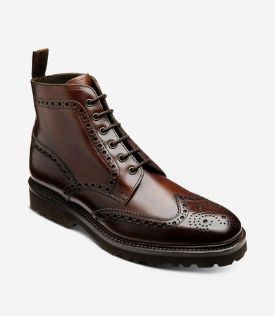 From a dynamic angle, the Pegasus boots reveal their meticulous craftsmanship and modern design. The rich dark brown waxy leather shines under the light, while the commando rubber soles provide traction and stability. The angled view accentuates the boots' sophisticated profile and rugged charm.