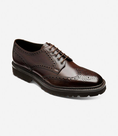 From a dynamic angle, the Perseus brogues reveal their meticulous craftsmanship and modern design. The rich dark brown calf leather gleams under the light, while the commando rubber sole provides traction and stability. The angled view accentuates the brogues' sophisticated profile and traditional charm.