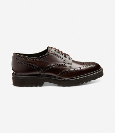 The Loake Perseus Dark Brown Derby Full-Brogue showcases a sleek silhouette, highlighting its hand-painted calf leather construction and sturdy commando rubber sole, epitomizing both style and durability.