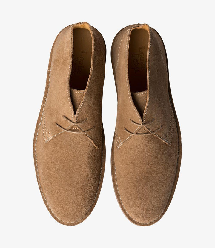 The top-down view of the Loake Sahara Tan Chukka Boot presents a clean and polished appearance, with the three eyelets and laces neatly arranged. The rounded toe design is evident, ensuring a comfortable fit while maintaining a sleek aesthetic. The premium suede leather appears smooth and inviting, and the fully leather-lined interior is suggested by the visible edges of the lining. This perspective highlights the boot’s versatility, making it suitable for various styles, from smart-casual to relaxed outing